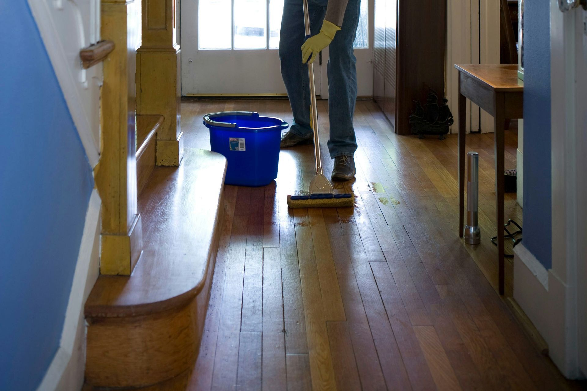 man in gray hoodie and blue denim jeans standing on brown wooden parquet flooring
